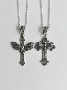Close-up of gothic silver cross necklaces with skull and wing relief details