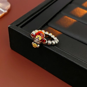 Detail of beaded dragon ring with red enamel charm on a black leather jewelry box