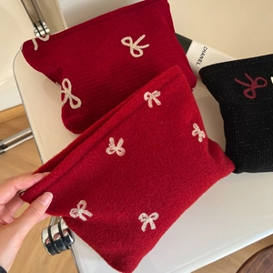 Close-up of soft felt makeup bags with detailed red and black bow embroidery design