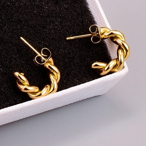 Macro detail of gold-plated twisted rope hoop earrings resting on a jewelry box