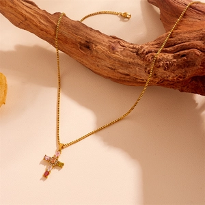 Detail view of gold cross necklace with colorful zircons placed on natural wood