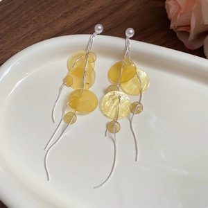 Detail of bamboo round shell tassel earrings with pearls on a ceramic tray