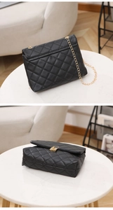 Detail of classic black quilted shoulder bag with gold chain strap and metal swivel lock