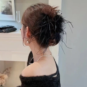 Detail view of large black feather hair clip styled on a woman's hair bun