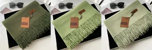 Detailed view of three shades of green cashmere scarves with tassels and brand labels