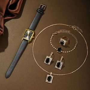 Flat lay of women's gold jewelry set with black gemstones and leather quartz watch