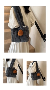 Detail of dark gray faux fur shoulder bag worn by model featuring brown plush charm accessory