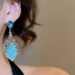 Detail of light blue crystal teardrop earrings with multi-color diamond accents on a model