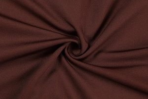 Detailed macro view of dark brown knitted fabric texture showing elasticity and soft drape