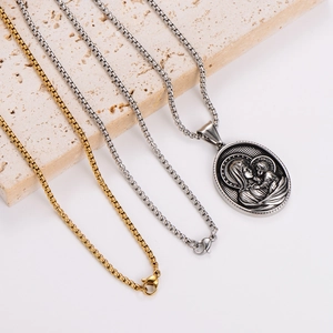 Oval embossed pendant necklaces in gold and silver finish on a stone platform