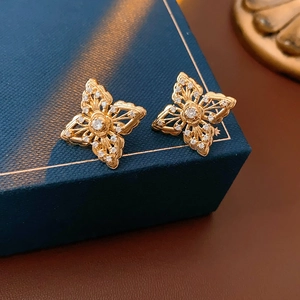 Macro shot of gold hollow flower stud earrings with intricate zircon inlay details
