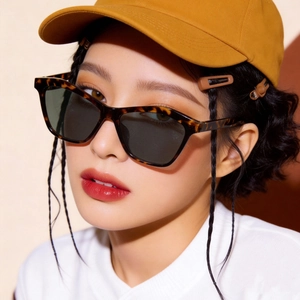 Close-up of leopard print cat-eye sunglasses worn by a model with a yellow cap