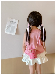 Close-up of pink cherry print bucket bag with gold chain strap on a young girl model