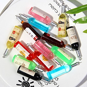 Detailed top view of 13 colorful resin mini wine bottle charms with metal rings on a white plate