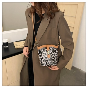 Close-up of leopard print bucket bag with brown trim and metallic twist lock detail
