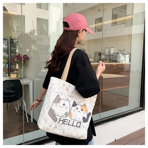Close-up of printed tote bag with cute cartoon cats and Hello text on model