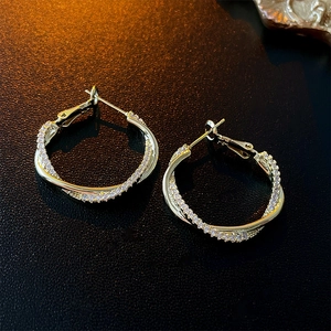 Détail des boucles d'oreilles torsadées plaquées or avec zircons sur cuir noir