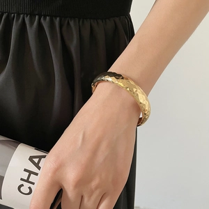 Vue détaillée d'un bracelet jonc doré avec des motifs géométriques taillés en diamant