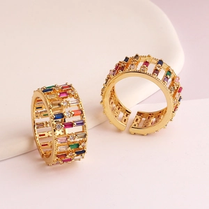 Close-up of gold wide rings featuring colorful baguette-cut cubic zirconia and open bands