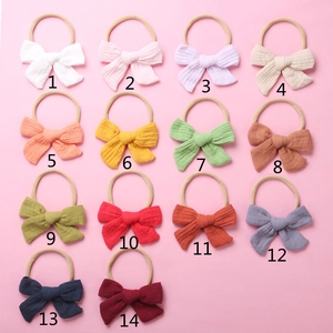 Collection of 14 colorful cotton muslin bow headbands for babies on pink background