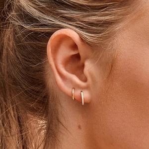Close-up of gold S925 silver wavy ear hoops with sparkling zircons on female ear