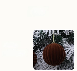 Close-up of brown striped Christmas ball with gold cap on a snowy pine branch