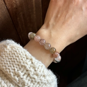 Detailed close-up of natural colorful rutilated quartz bead bracelet on model's wrist