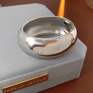 Close-up of a wide polished silver cuff bracelet with a hinge clasp on a jewelry box