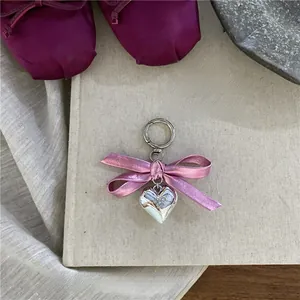 Detailed shot of silver heart charm and pink ribbon keychain on vintage book background