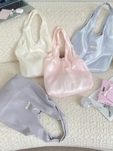 Elegant satin tote bags in soft pastel colors displayed on a plush textured background