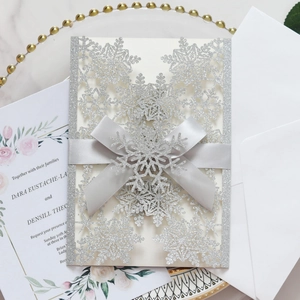 Silver laser-cut snowflake wedding invitation with glitter finish and elegant bow detail