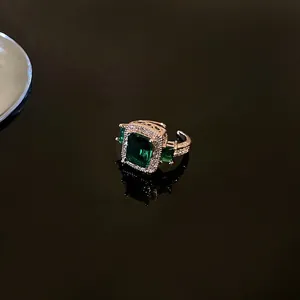 Macro shot of silver ring with emerald green stone and sparkling cubic zirconia halo