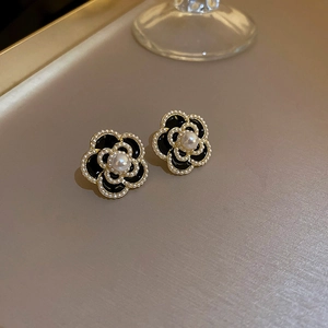 Detail of vintage enamel camellia earrings with gold trim and delicate pearl accents