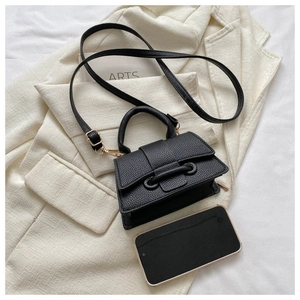 Top view of a black pebble texture mini handbag with handle and strap on an elegant blazer