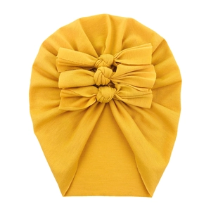 Detail of yellow soft cotton baby turban hat featuring three decorative bows