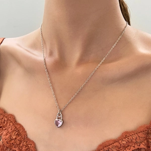 Detail der silbernen Halskette mit rosa Herz-Zirkonia-Anhänger an einem weiblichen Model