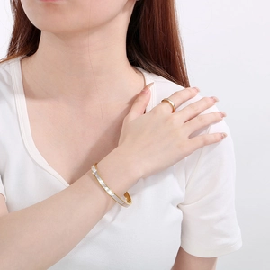 Detailed view of a gold-plated stainless steel jewelry set with white shell inlay
