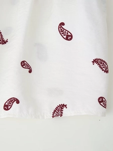 Detailansicht von weißem Stoff mit bordeauxrotem Paisley-Muster und Baumwollmischtextur