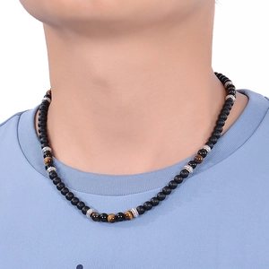 Close-up of beaded necklace with matte black stones and tiger eye worn by a male model