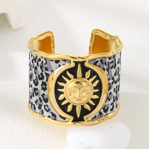 Detail of bohemian gold cuff bracelet with leopard print texture and embossed sun face
