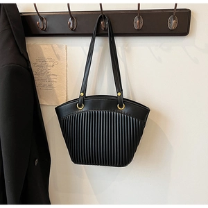 Detail of black pleated tote bag hanging on wooden hook with metallic gold rings