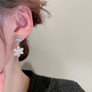 Close-up of sparkling zircon flower earrings featuring crystal petal details and silver pins