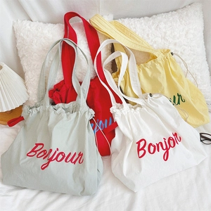 Macro shot of colorful drawstring canvas tote bags featuring Bonjour print detail