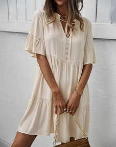 Détail d'une robe beige à col en V avec boutons, manches à volants et tissu léger