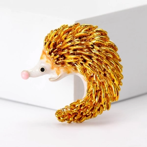 Detail view of a hedgehog brooch with gold textured quills and white face detail