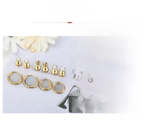 Detail of 10-piece gold geometric earrings set with zircon and pearls on light blue surface