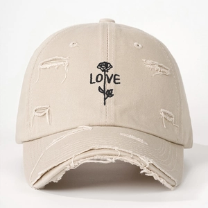 Detailed close-up of rose and LOVE embroidery on a distressed khaki baseball cap