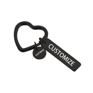 Close-up of black custom keychain with heart ring and engravable tags on white background