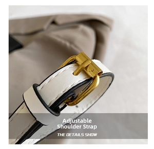 Detail view of the adjustable white leather shoulder strap with gold buckle and black edges
