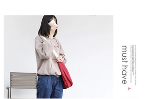 Detail of red canvas crossbody bag with casual grey hoodie and minimalist styling